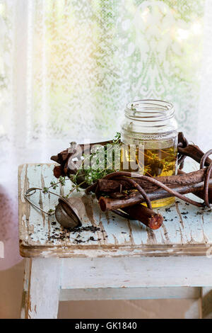 Glas heißer Kräutertee mit Bund frischer Thymian, serviert mit Vintage Teesieb auf alten Holzstuhl mit Fenster im backg Stockfoto