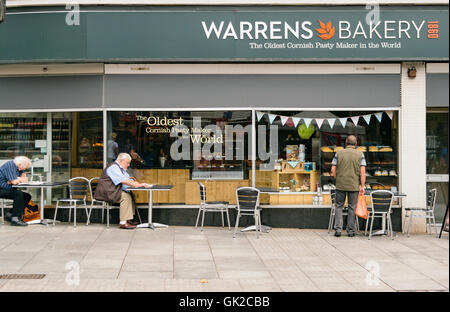 Exeter, Devon, Großbritannien - 17. August 2016: Leute die Zeitung lesen und betrachten Gebäck im Fenster Warrens Stockfoto