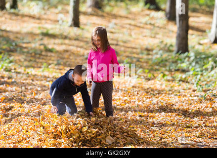 Kinder spielen mit gefallene Herbstlaub im park Stockfoto