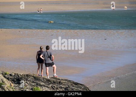 Zwei Menschen stehen auf Ost Pentire und blicken auf Crantock Beach in Newquay, Cornwall. Stockfoto