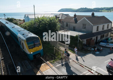 Arriva Zug passiert Barriere von einem Bahnübergang am Bahnhof Ferryside, Küste, Küste, Carmarthenshire, West Wales, Großbritannien Stockfoto