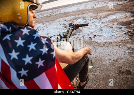 Porträt von einem brutalen Mann mit Goldhelm und amerikanische Flagge auf dem Motorrad sitzen hautnah Stockfoto