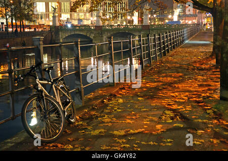 Fahrrad ruht gegen einen Zaun an einem Stadt-Kanal in der Nacht, im Herbst in Berlin, Deutschland. Stockfoto