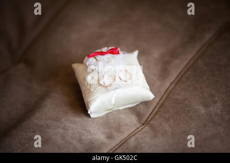 Goldene Hochzeit Ringe auf geschmückten kleinen weißen Kissen. Ehe-Konzept Stockfoto