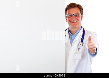 lächelnde Arzt mit Werbefläche hält Daumen hoch. Stockfoto