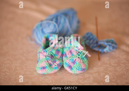 Gestrickte Babyschuhe auf einem Sofa, handgefertigt Stockfoto