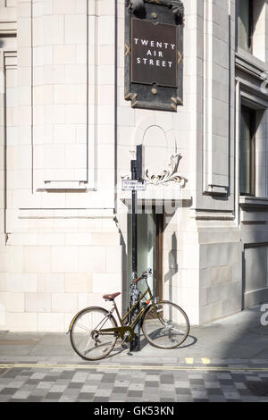 Ein altes Fahrrad ist an einen Laternenpfahl an der Ecke der Straße in London gesperrt Stockfoto