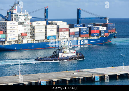 Ein großer Schlepper entlang eine riesige, geladene CMA CGM-Frachter in St. Maarten Stockfoto