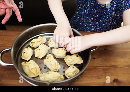 Kochen mit Kindern. Kleines Mädchen gelehnt wie Manti (Zentralasien Knödel) zu machen. Manti sind fertig geladen werden Stockfoto