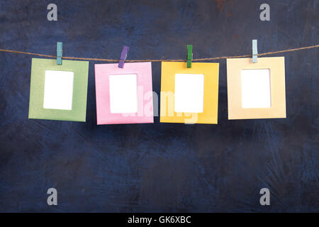 Vier Bilder hängen am Seil auf dunklem Hintergrund Stockfoto