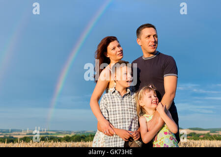 glückliche Familie auf einer Wiese vor Regenbogen Stockfoto