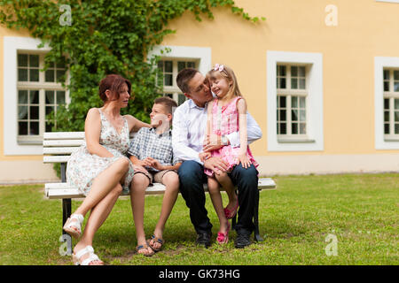 Familie sitzt vor ihrem Haus Stockfoto