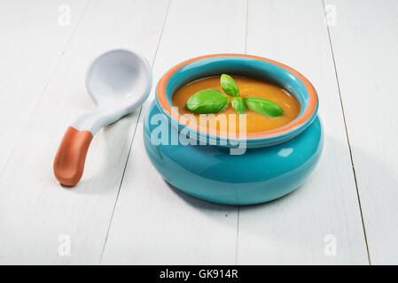 frische Kürbissuppe in Keramikschale mit Löffel auf einem alten hölzernen Hintergrund Stockfoto