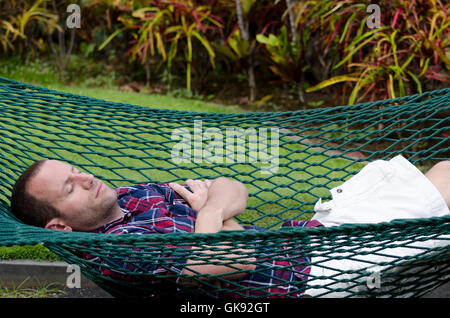 Schlafen in einer Hängematte mit seinen armen Mann gekreuzt und die Augen geschlossen. Stockfoto