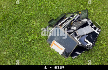 Grosser Haufen die gebrochenen und gerissenen zellulären Telephons und Tabletten liegen auf dem grünen Rasen Rasen. Moderne Technologien verschmutzen enviro Stockfoto