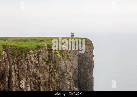 Zwei Wanderer nahe an den Rand der vertikalen Klippen in der Nähe von Elegug Stacks in Pembrokeshire Coast National Park, Wales, Großbritannien Stockfoto