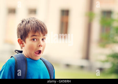 Junge mit Rucksack infront von einem Schulgebäude Stockfoto