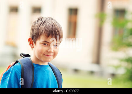 Junge mit Rucksack infront von einem Schulgebäude Stockfoto