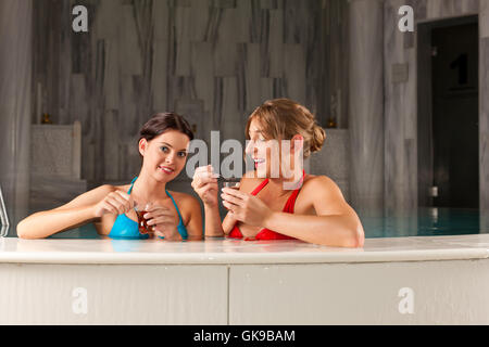 zwei Freundinnen im Pool Tee trinken Stockfoto