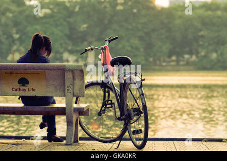 Hanoi, Vietnam - 28. August 2011: das Mädchen sitzt auf der Bank neben ihr Fahrrad am Hoan-Kiem-See Stockfoto