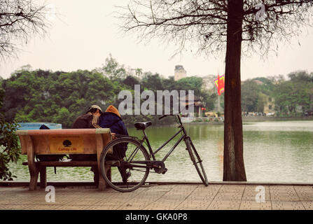 Hanoi, Vietnam - 10. März 2012: das Paar auf der Bank neben ihrem Fahrrad sitzen am Hoan Kiem Lake Stockfoto