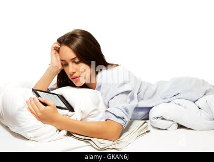 junge Frau im Bett mit dem Ebook zu lesen Stockfoto