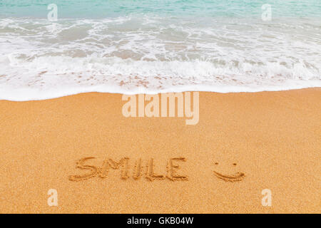 Naturbelassener schöner Strand am blauen Meer mit Inschrift "SMILE" am sand Stockfoto