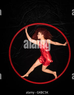 Junge rothaarige Frau in einem roten Kleid in einem roten ring Stockfoto