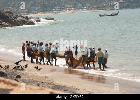 Fishermenn ziehen Netto in Kovalam Beach von Leela, Kovalam, Indien. Stockfoto