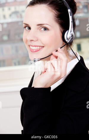 junge Brünette Frau arbeitet in einem Call-Center mit Kopfhörer Stockfoto