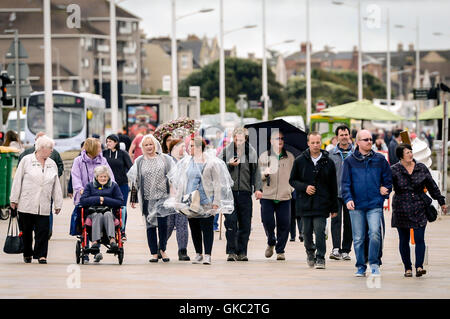 Menschen zu Fuß entlang der Strandpromenade in Weston-super-Mare, wo eine Änderung des Wetters genommen hat halten in der Küstenstadt Somerset und böig Bedingungen ersetzen der heißen Sonne der letzten Tage. Stockfoto