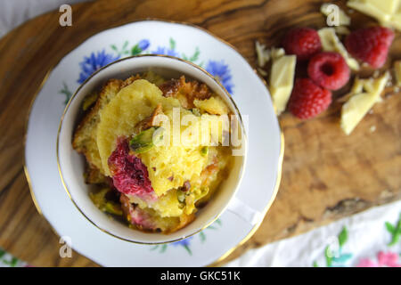 Bread And Butter Pudding im Cup. Holzbrett mit Himbeeren und weißer Schokolade. Stockfoto