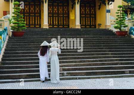 Vietnamesische Mädchen, konische Hut und Ao Dai (Vietnamesische Tracht oder langes Kleid) im Saigon Zoo, Ho Chi Minh City, Vietnam Stockfoto