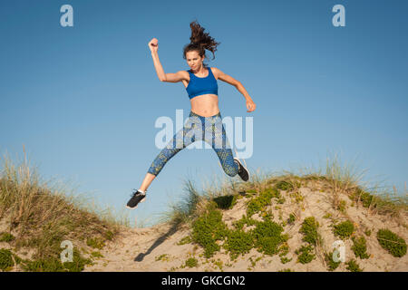 Frau, Sport, laufen und springen in Sanddünen Stockfoto