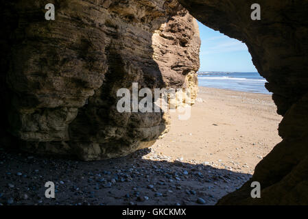 Höhlen von Klippen von Gelben magnesiumhaltigen Kalkstein in Seaham Strand, County Durham, UK erodiert Stockfoto