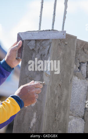 Arbeiter verwenden Eisen Herrscher Snd Kelle Verputzen die Pole auf Baustelle Stockfoto