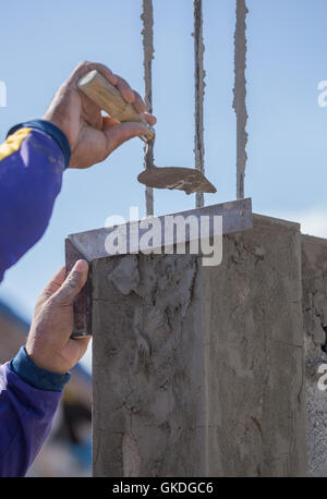 Arbeiter verwenden Eisen Herrscher Snd Kelle Verputzen die Pole auf Baustelle Stockfoto