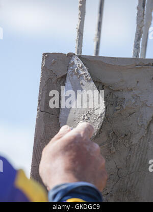 Worker nutzen Kelle Verputzen die Pole auf Baustelle Stockfoto