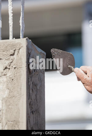 Worker nutzen Kelle Verputzen die Pole auf Baustelle Stockfoto