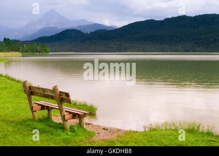 Bank im grünen Park und See in Alpen Stockfoto