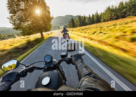 Motorradfahrer fahren auf der Autobahn im schönen Abendlicht. Schuss aus Fahrersicht Sozius Stockfoto