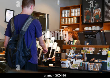 Mann Kaffee kaufen und bezahlen per Kreditkarte innerhalb Starbucks Filiale hautnah Stockfoto