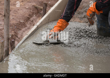 Hand der Erbauer Arbeiter benutzen Kelle Verputzen einen neu gegossenen Betonboden Stockfoto