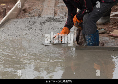 Hand der Erbauer Arbeiter benutzen Kelle Verputzen einen neu gegossenen Betonboden Stockfoto