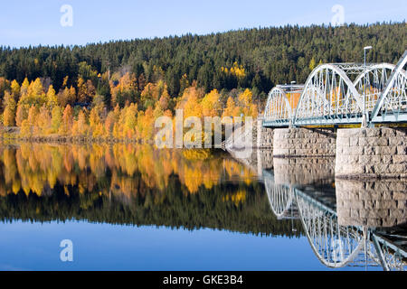 Herbst/Herbst Bäume reflektiert perfekt in einem langsam bewegenden Fluss neben Metall und Stein Brücke in Järpen, Schweden Stockfoto
