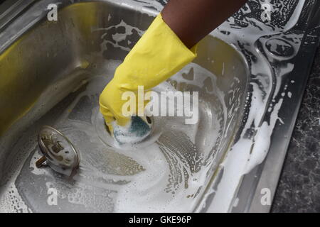 Hand mit Handschuhen, die Reinigung der Wanne Stockfoto