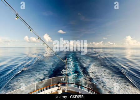 Kreuzfahrt Schiff Gefolge nur Heck des Schiffes und schöne blaue Meer und Himmel mit weißen Wolken zu zeigen. Rauchspuren vom Schiff. Stockfoto