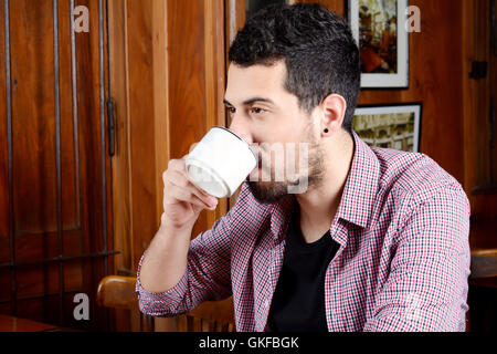 Porträt des lateinischen Jüngling, trinken Kaffee in einem Café. Im Innenbereich. Stockfoto