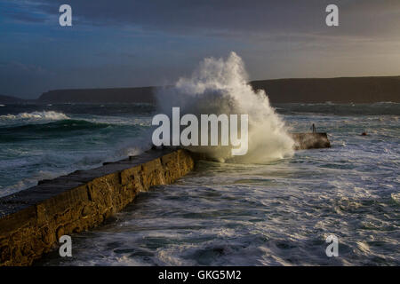 Große Wellen über die Pier in Sennen bei einem Wintersturm. Stockfoto