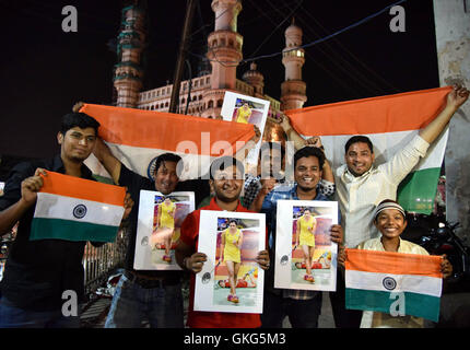 Hyderabad, indischen Bundesstaat Telangana. 19. August 2016. Hyderabadi Jugend halten die Plakate der indische Badmintonspielerin P. V. Sindhu feiern ihren Gewinn der Silber für der Frauen Medaille Einzel Finale der Rio-Olympische Spiele 2016 gegen Spaniens Carolina Marin vor einem riesigen Bildschirm Gopichand Academy in Hyderabad, südindischen Bundesstaat Telangana, 19. August 2016. © Stringer/Xinhua/Alamy Live-Nachrichten Stockfoto